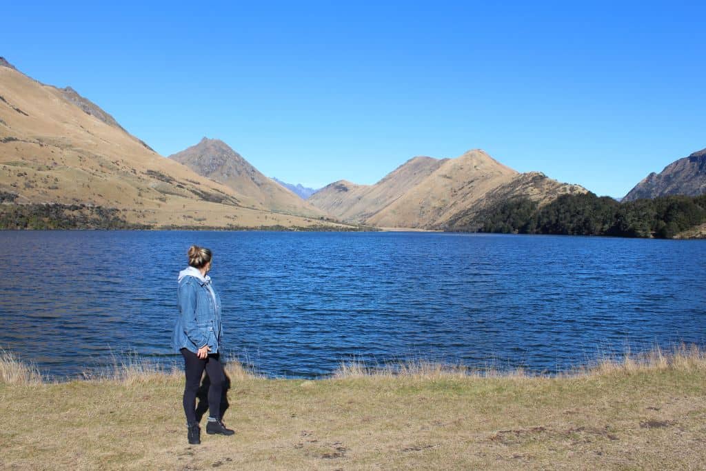 Girl standing in front of Moke Lake with mountains in the background