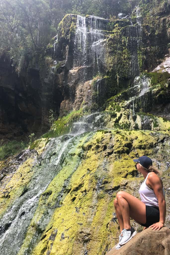 Woman sitting in front of the waterfall waterfall Mokoroa Falls.