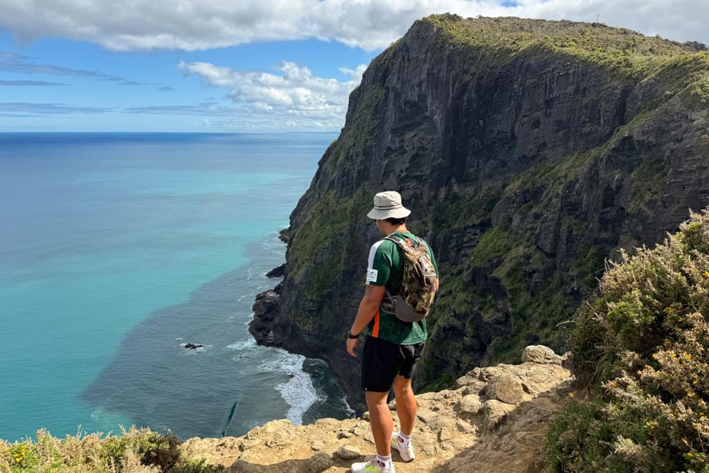 Man looking over the edge of a cliff at the water at the Mercer Bay Loop Walk.