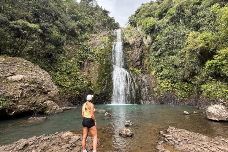 Woman standing in front of the waterfall Kitekite Falls.