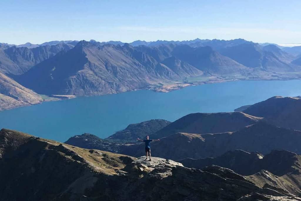 Man standing at the top of the Ben Lomond Hike with lake Wakatipu in the background.