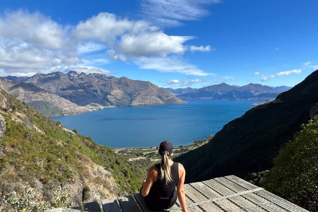 Girl sitting on the edge of the platform on the Wye creek walk in Queenstown looking out at the view.