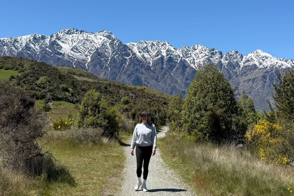 Girl walking down a gravel track with mountains in the background in Queenstown.