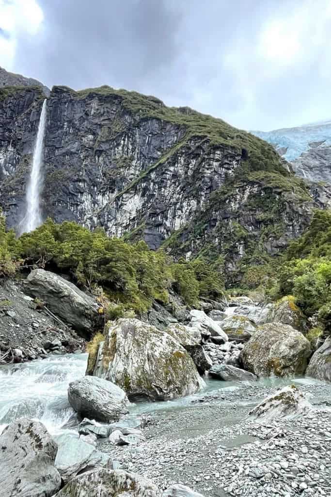 A mountainous scene with the waterfall and glacier on the Rob Roy Glacier Walk.