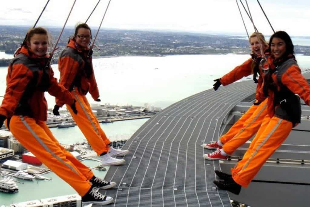 4 girls walking along the outside of the Skytower, doing the SkyWalk.