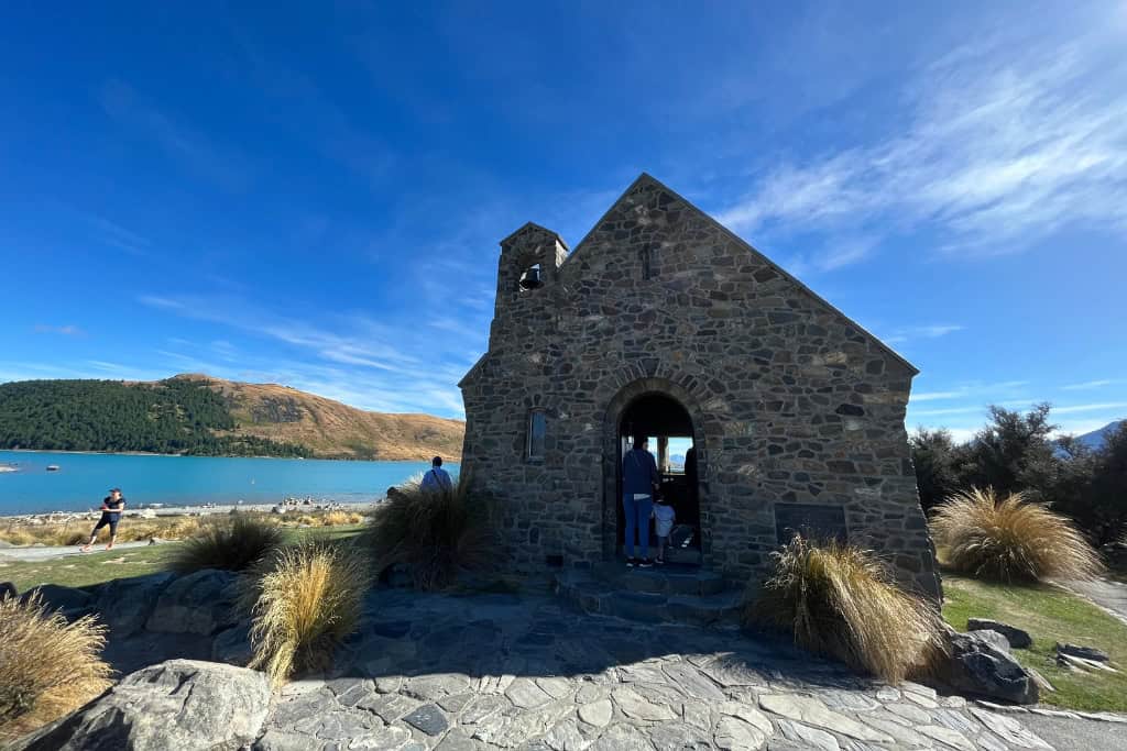 A small stone church sitting on the edge of Lake Tekapo