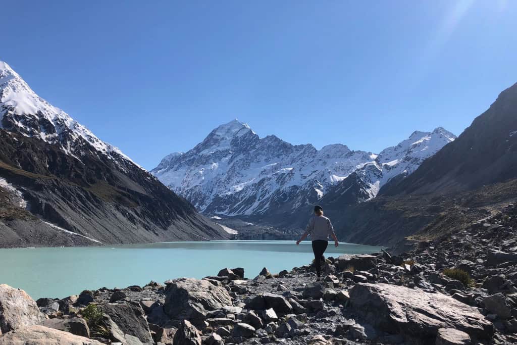 Person standing on a rock in front of Mt Cook, on of the best day trips from Tekapo.