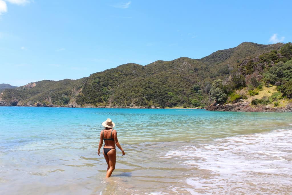 Woman standing in the water and looking out to the ocean.