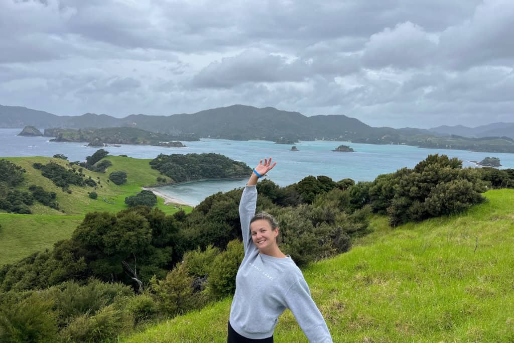 Woman with her arms in the air at the lookout to Urupukapuka Bay.