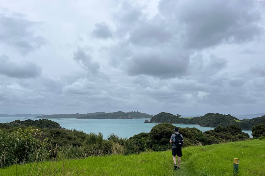 Man walking along one of the tracks with the ocean in the background.