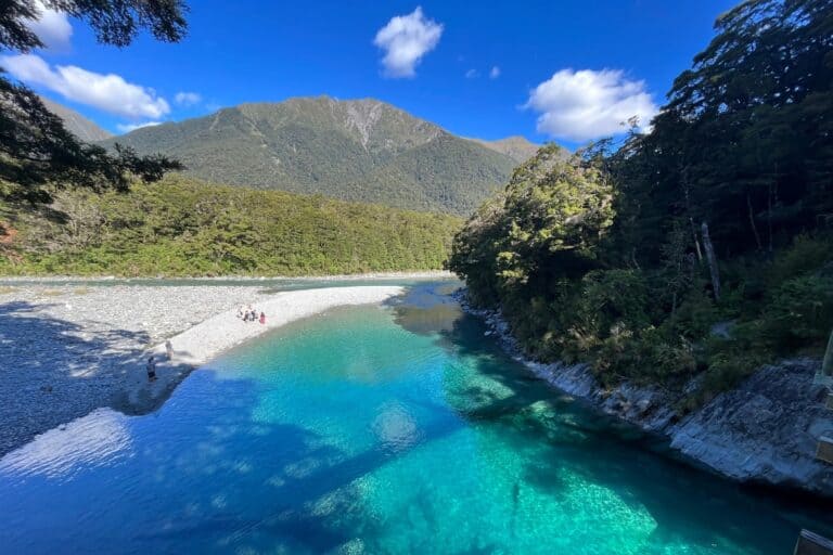 The bright blue river at the Blue Pools with mountains towering in the background.