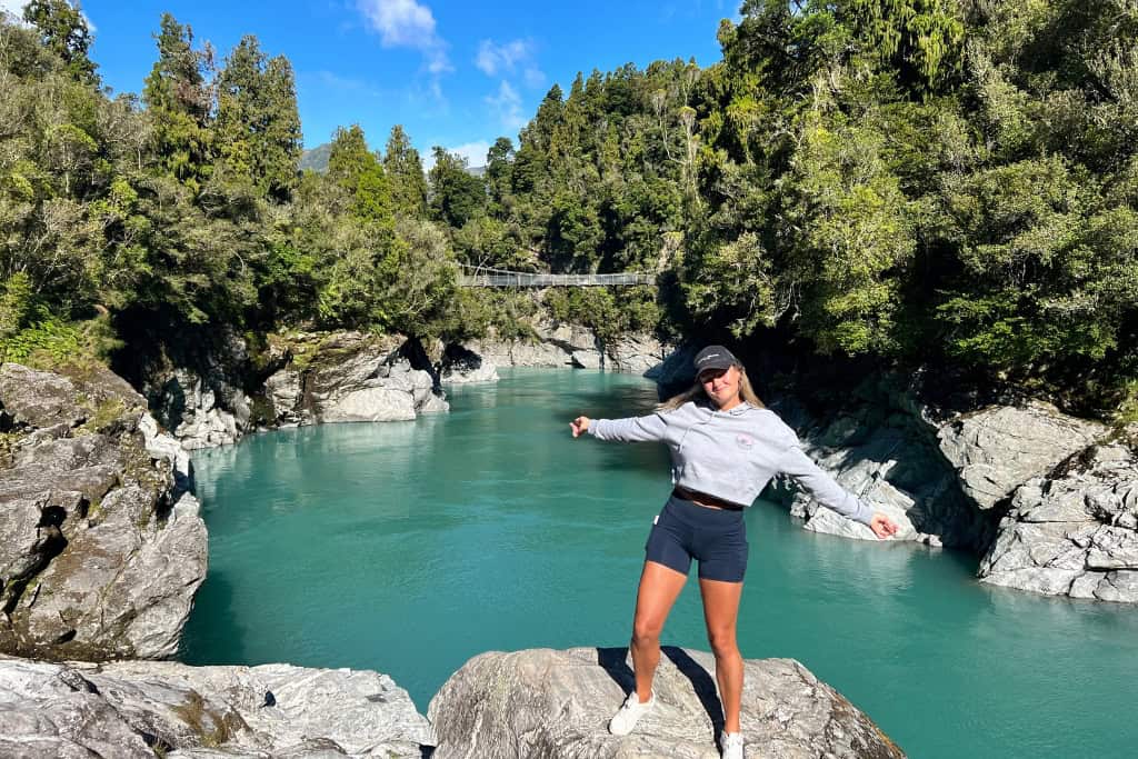 Woman standing on the rocks at the Hokitika Gorge, one of the most popular things to do.