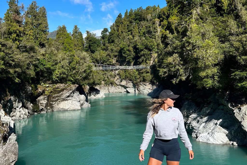 Woman stands on the edge of the river at the Hokitika Gorge.