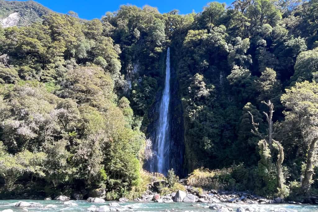 Thunder Creek Fall standing tall over the blue water below.