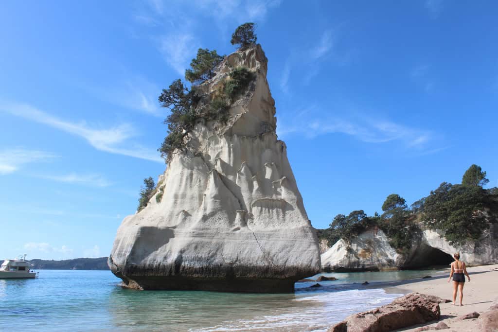 A tall rock formation standing tall as waves crash around it.