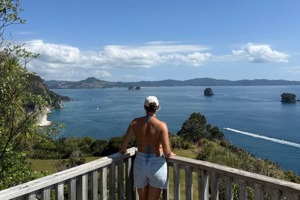 Woman standing at one of the lookouts along the Cathedral Cove walk, looking at the ocean.