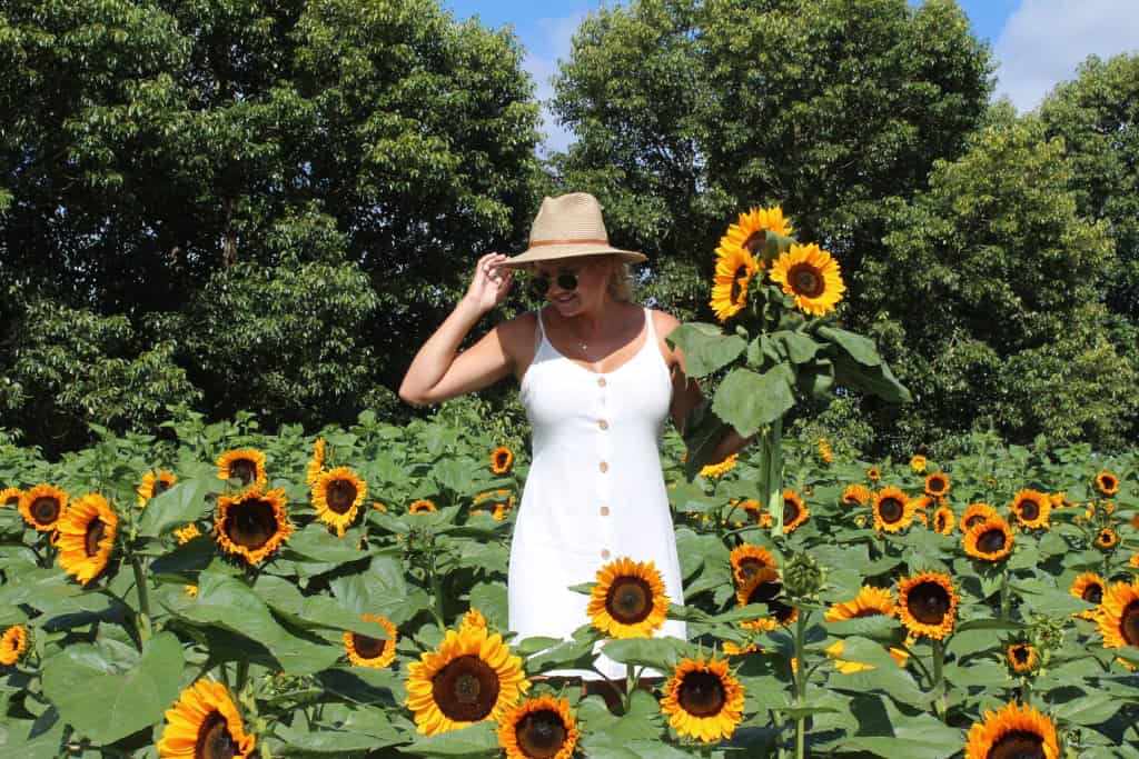 Woman holding a bunch of flowers in a field of sun flowers.