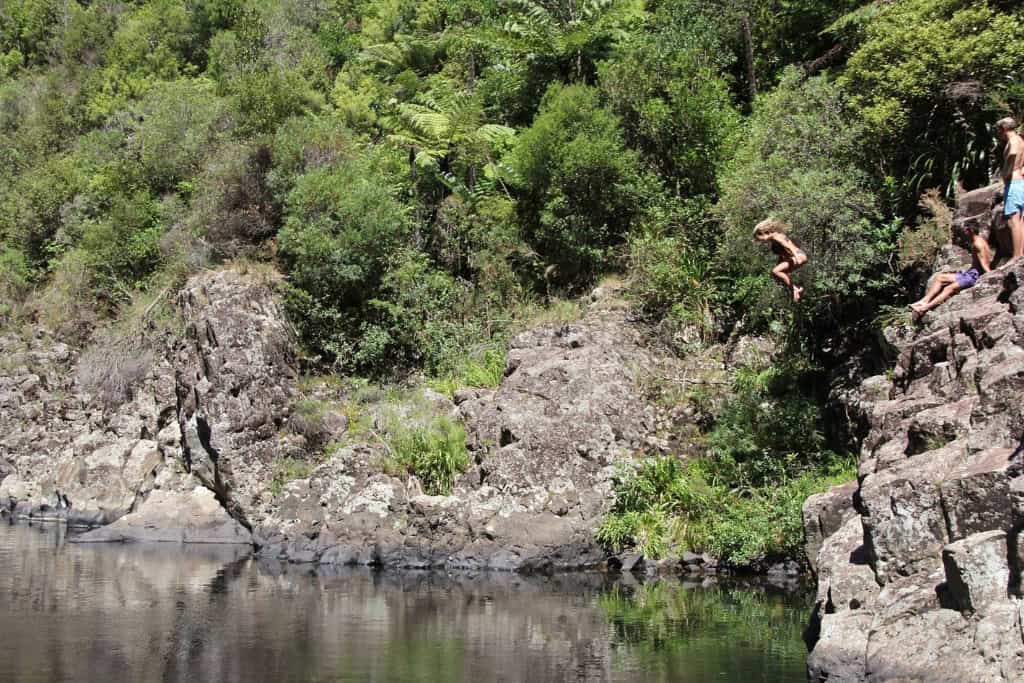 Woman jumping off the rocks into the river below.