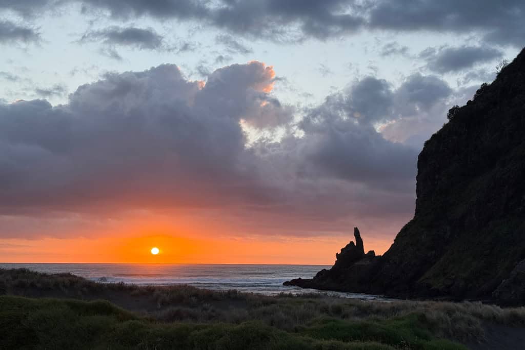 The sun setting over the water at Piha. 