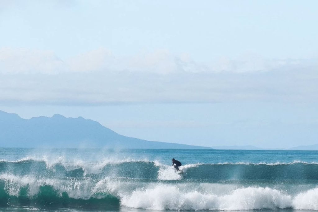A person surfing at one of the beaches near Matakana on a day trip from Auckland. 