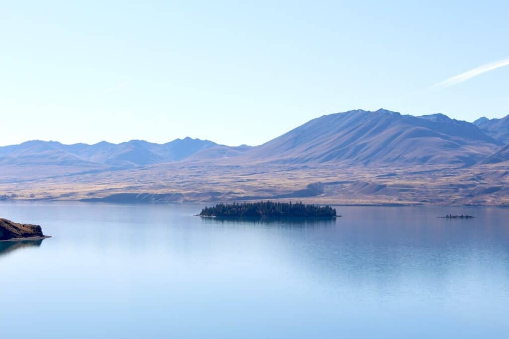 An island in surrounded by water in the middle of Lake Tekapo.