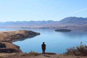Woman walking the Mt John Summit Track looking out at the blue water of Lake Tekapo.