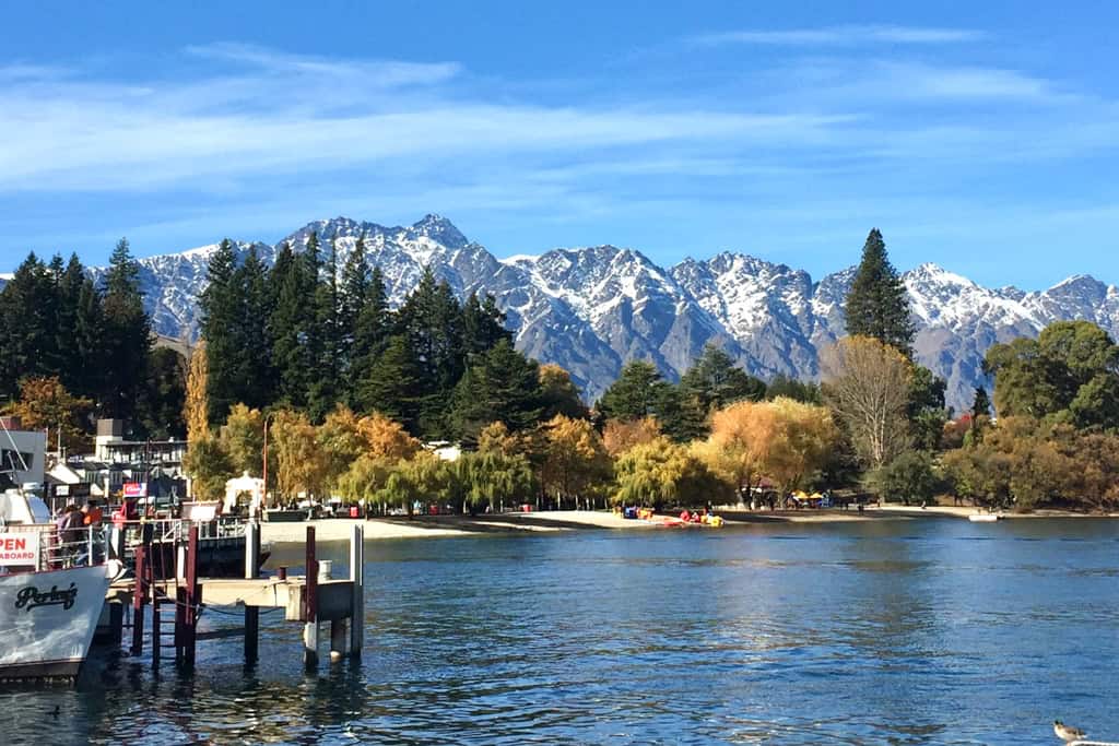 Autumn colours fill the trees surrounded by snow covered mountains in Queenstown.