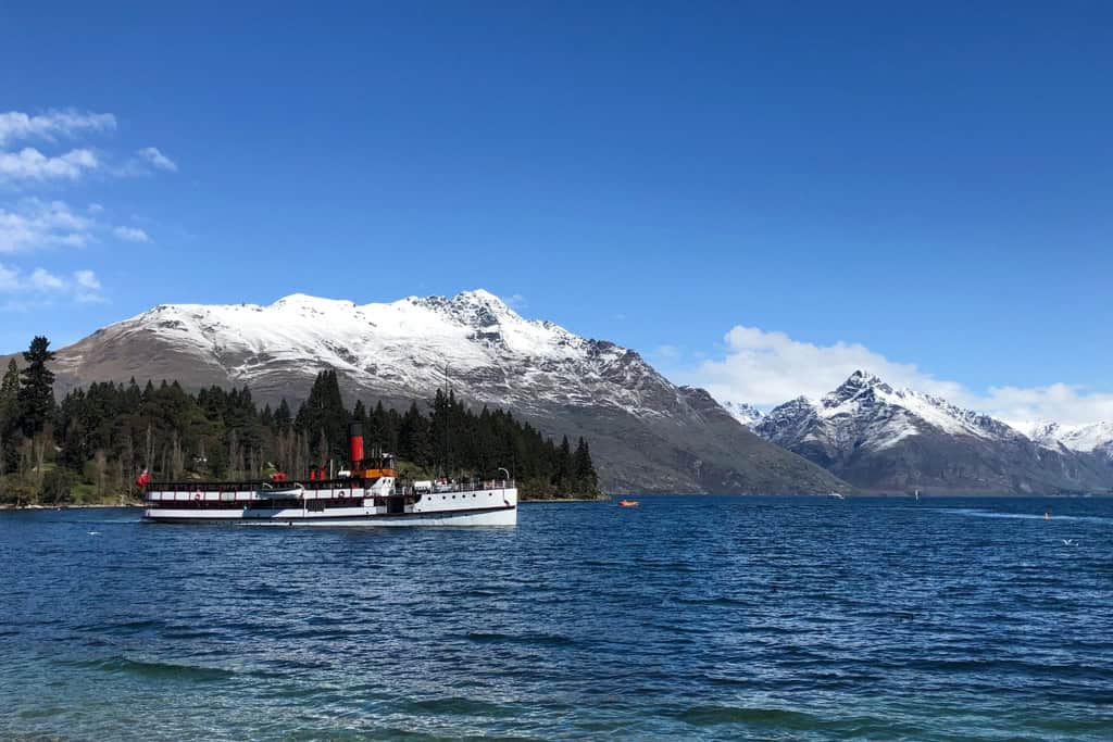 The old TSS Earnslaw moving slowly across the lake in front of snowy mountains.