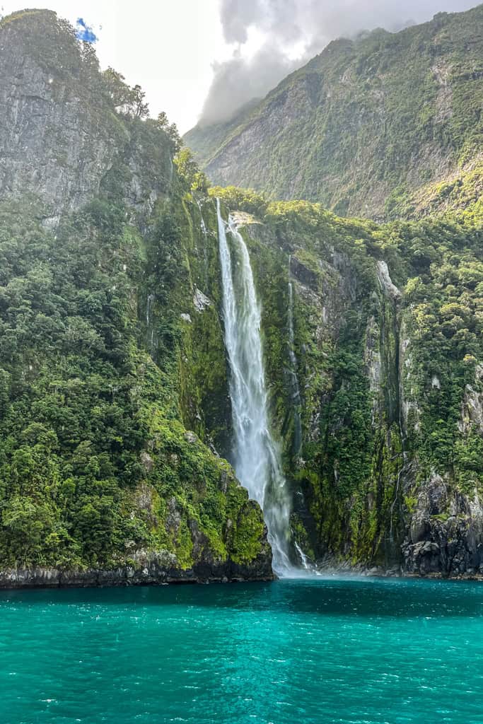 A waterfall coming off the mountains into the water in Milford Sound.