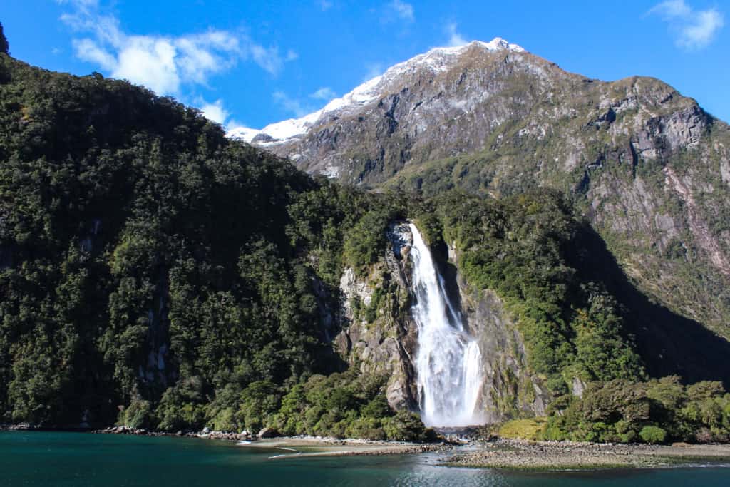 Water falls from Bowen Falls into the water of Milford Sound.