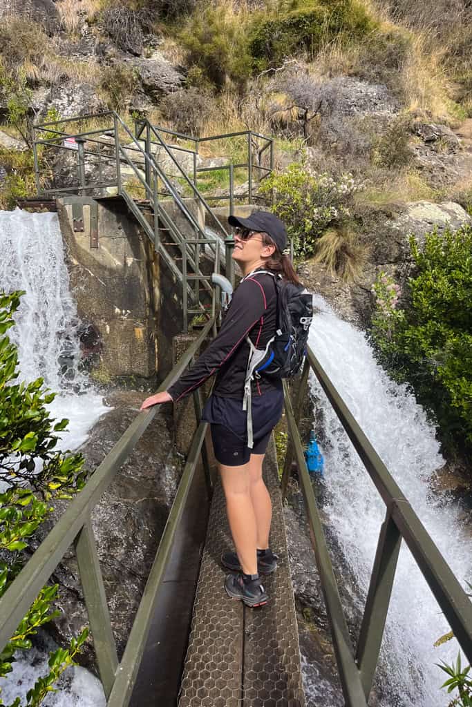 Woman standing on the old dam looking at the water falling around her.