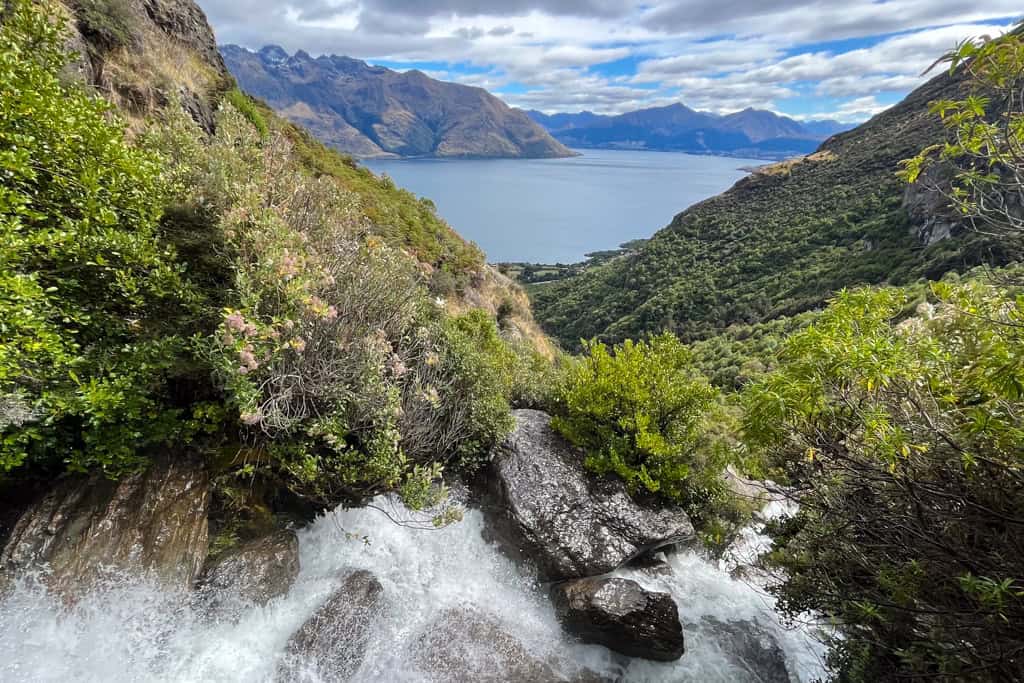 The view of the lake and the mountains at the waterfalls flows down the rocks.