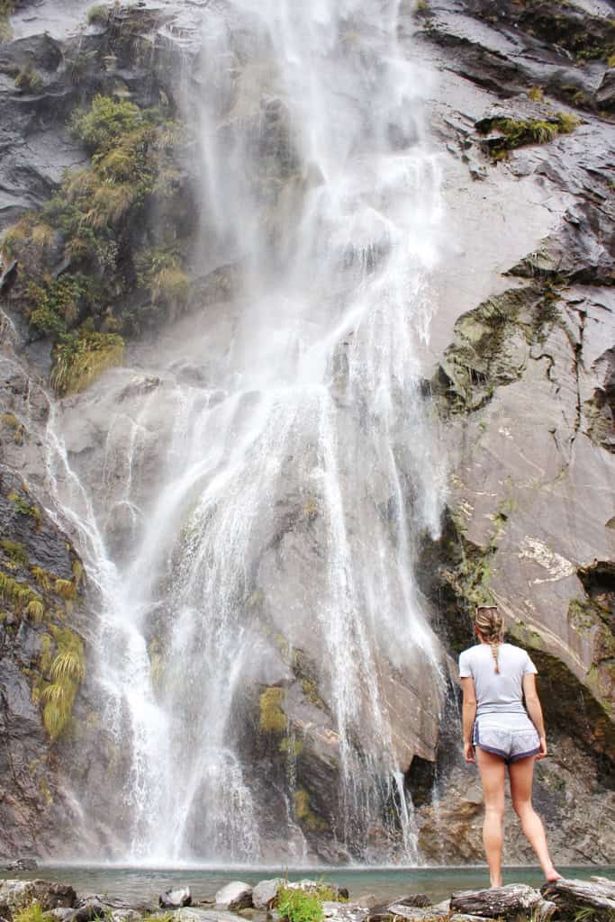 Water crashes down the falls as a person stands and watches with enjoyment.